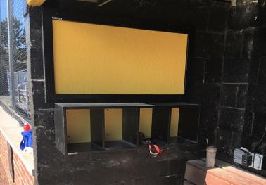 4 Helmet Cubby Rack mounted on a black wall, designed to hold baseball or softball player helmets.
