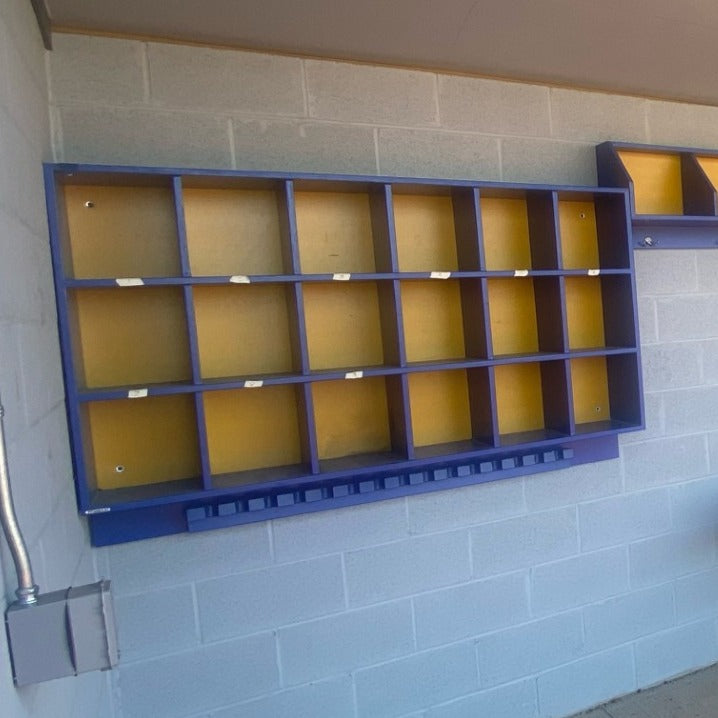 Blue and yellow storage unit mounted on a gray tiled wall.
