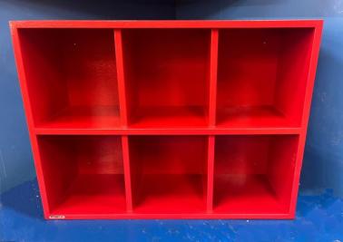 A red wooden 6 Helmet Cubby Rack designed to store baseball or softball player helmets, with individual compartments.