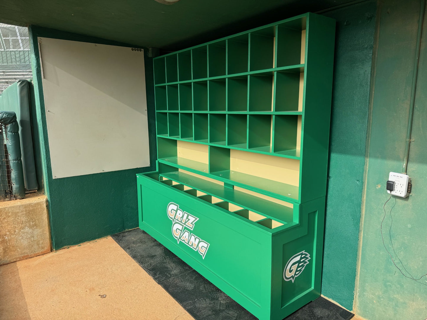 Green booth with shelves and a whiteboard inside a room.
