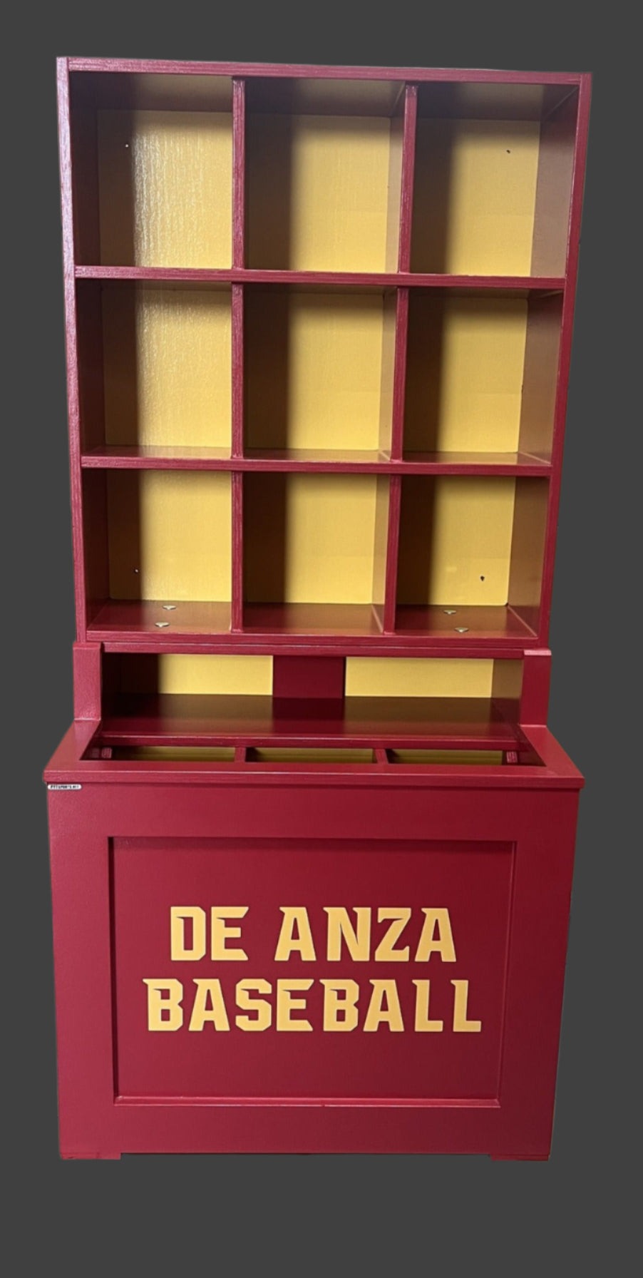Red bookshelf with 'De Anza Baseball' text in a warehouse setting