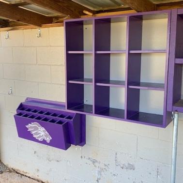 A purple 9 Helmet Cubby Rack mounted on a white wall, designed for storing baseball or softball helmets.