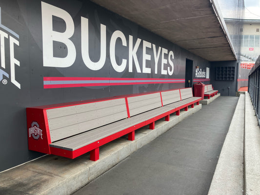 Buckeyes-themed dugout with red and gray benches against a wall with 'Buckeyes' branding.
