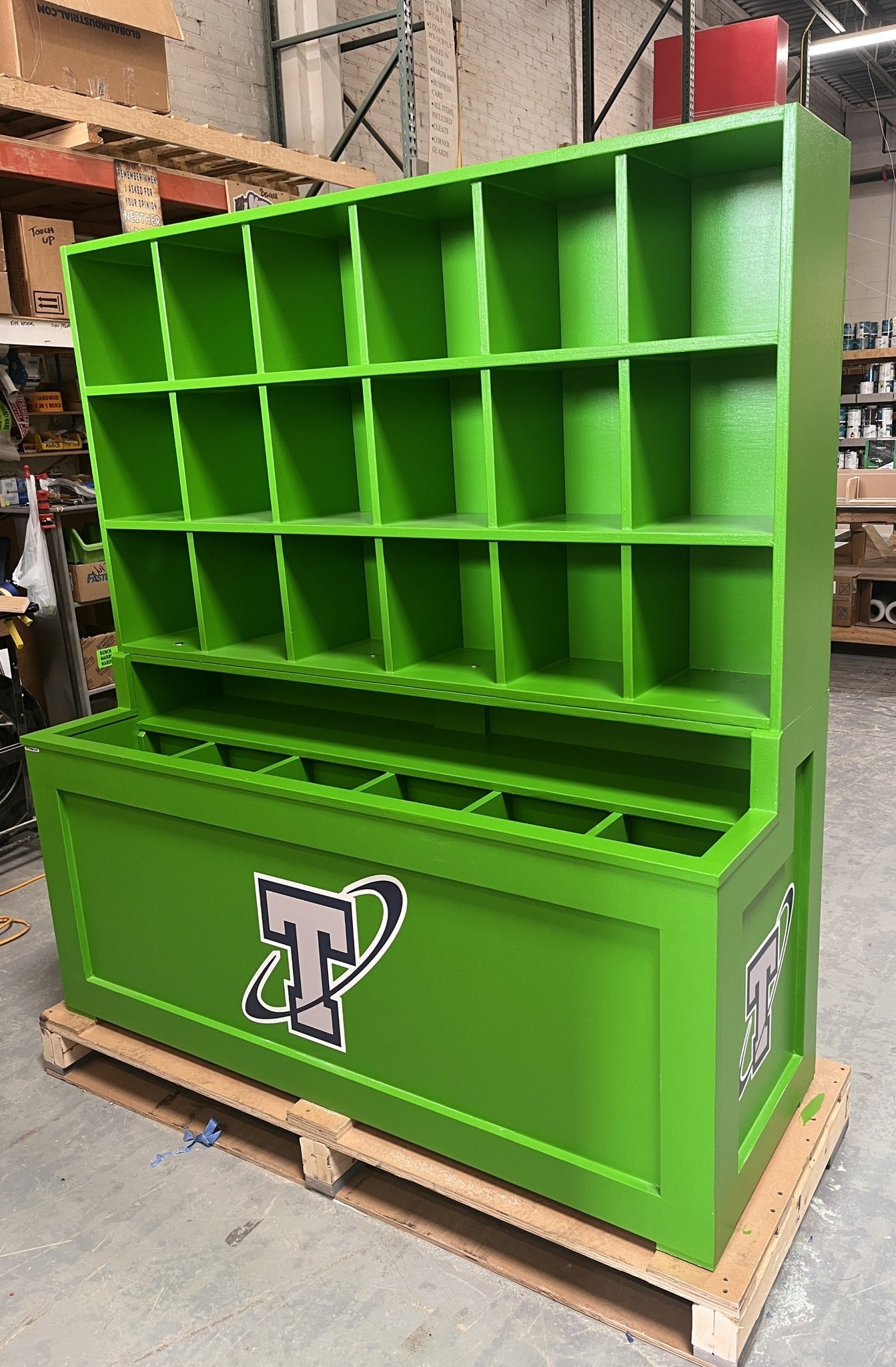 Green storage unit with multiple compartments on a pallet in a warehouse setting.