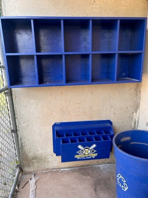 A blue wooden 10 Helmet Cubby Rack designed for storing baseball or softball helmets, with individual compartments, mounted on a wall.