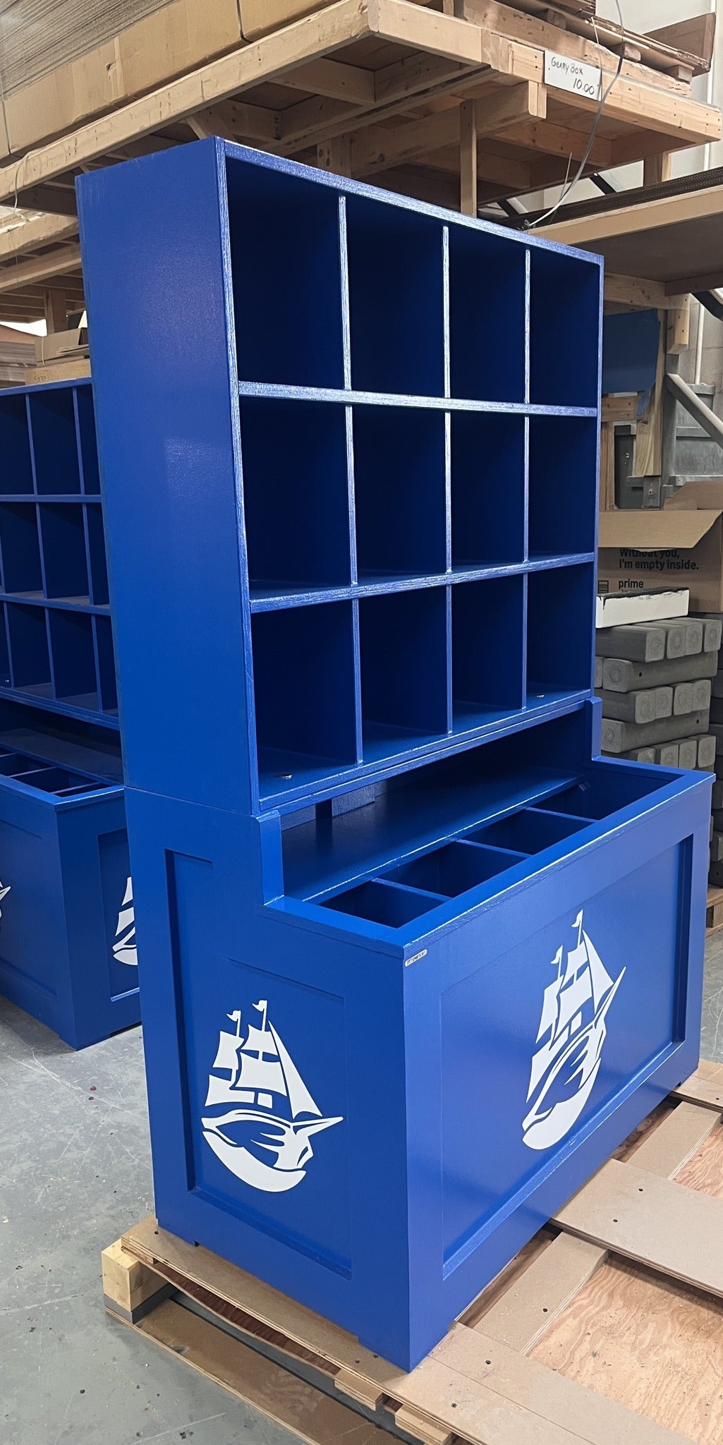 Blue storage unit with a ship logo on a wooden pallet in an industrial setting
